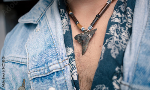 Shark tooth necklace on hairy chest and jean jacket photo