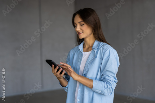 Fényképezés Young woman stand holds smart phone enjoy distant chat with friend, share messag