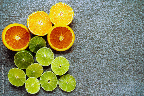Fototapeta Naklejka Na Ścianę i Meble -  Various citrus and juicy lime and orange slices on gray stone background from above. Place to insert text.