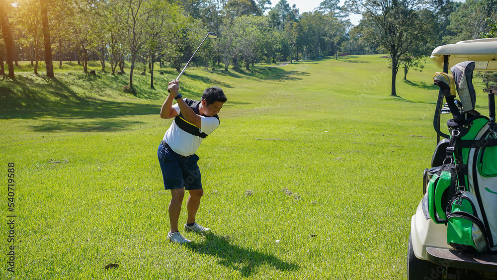 Fototapeta premium Golfer playing golf in the evening golf course, on sun set evening time.