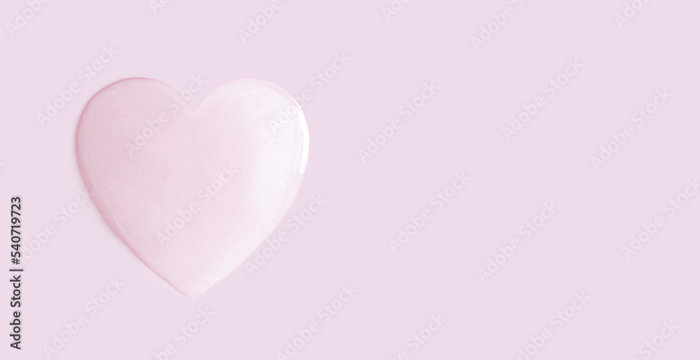 drop of cosmetic essence of serum gel on a light pastel background in the shape of a heart