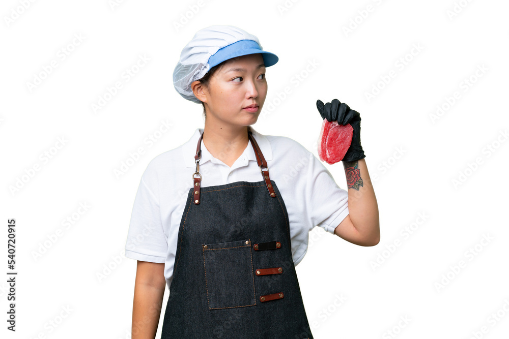 Young caucasian woman wearing an apron and serving fresh cut meat over isolated background looking to the side Young caucasian woman wearing an apron and serving fresh cut meat over isolated background looking to the side