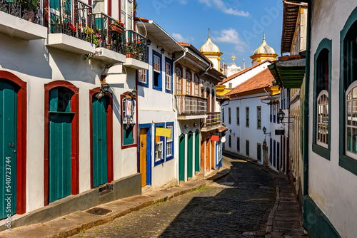 Bucolic street with old colonial-style houses and sunlit cobblestones in the historic city of Ouro Preto in Minas Gerais photo