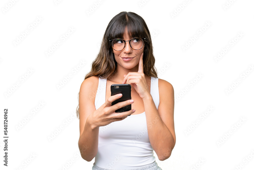 Young caucasian woman over isolated background using mobile phone and thinking Young caucasian woman over isolated background using mobile phone and thinking