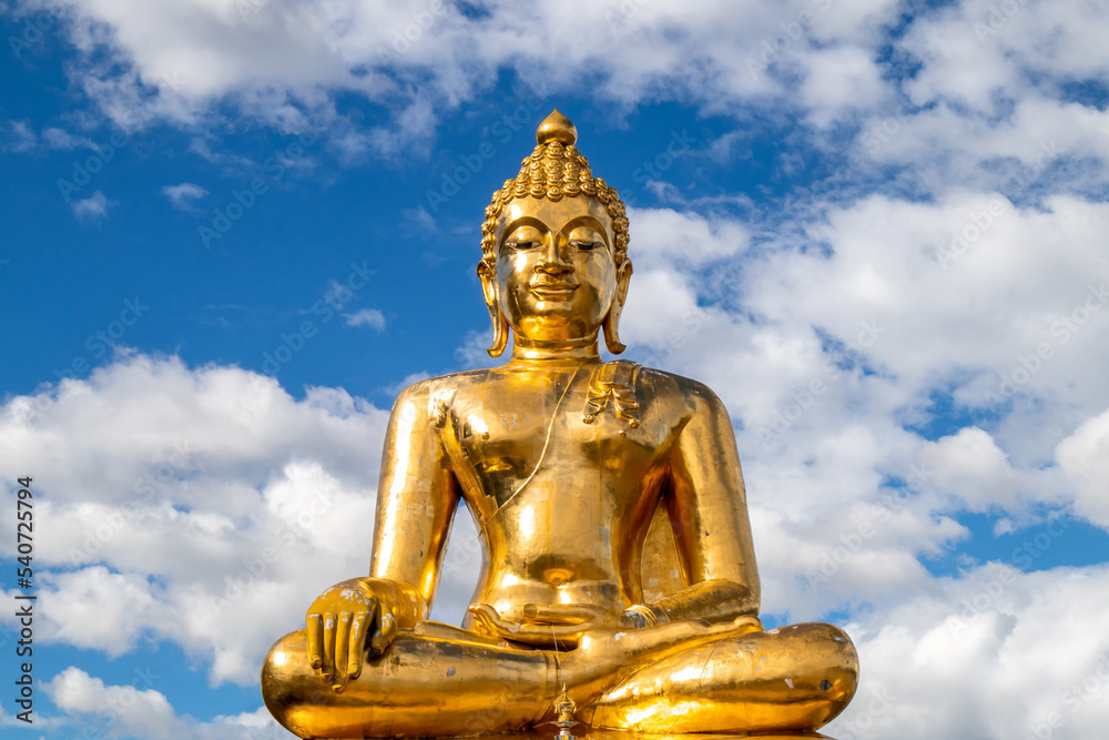The grand golden Buddha image with the light blue sky and white cloud in Chiang Rai province , Thailand. 