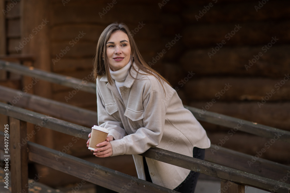Young happy woman relaxing with hot tea or coffee on the cozy terrace of a wooden country house. Autumn cozy day. Young happy woman relaxing with hot tea or coffee on the cozy terrace of a wooden country house. Autumn cozy day.