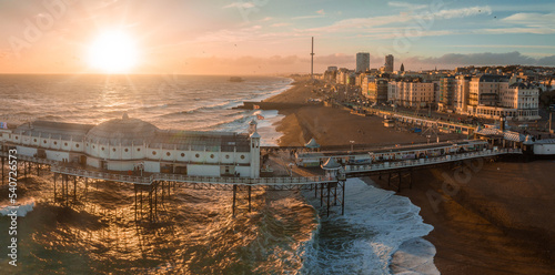 Aerial view of Brighton Palace Pier, with the seafront behind. Aerial shot of the stunning city of Brighton and Hove with seagulls flying around at sunset. photo