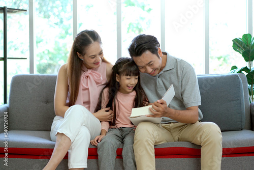 Happy Asian family, father, mother, and daughter living together in the living room. 