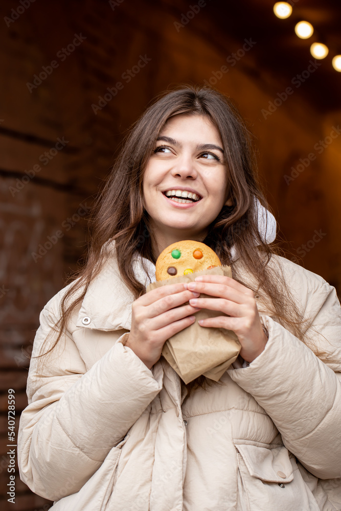 Attractive young woman with gingerbread on a blurred background with bokeh.