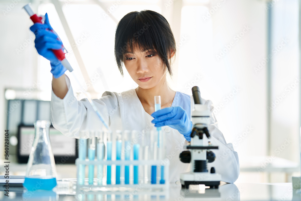 Female scientist making microbiology research using pipette, flask and test tubes working in modern chemical lab Female scientist making microbiology research using pipette, flask and test tubes working in modern chemical lab