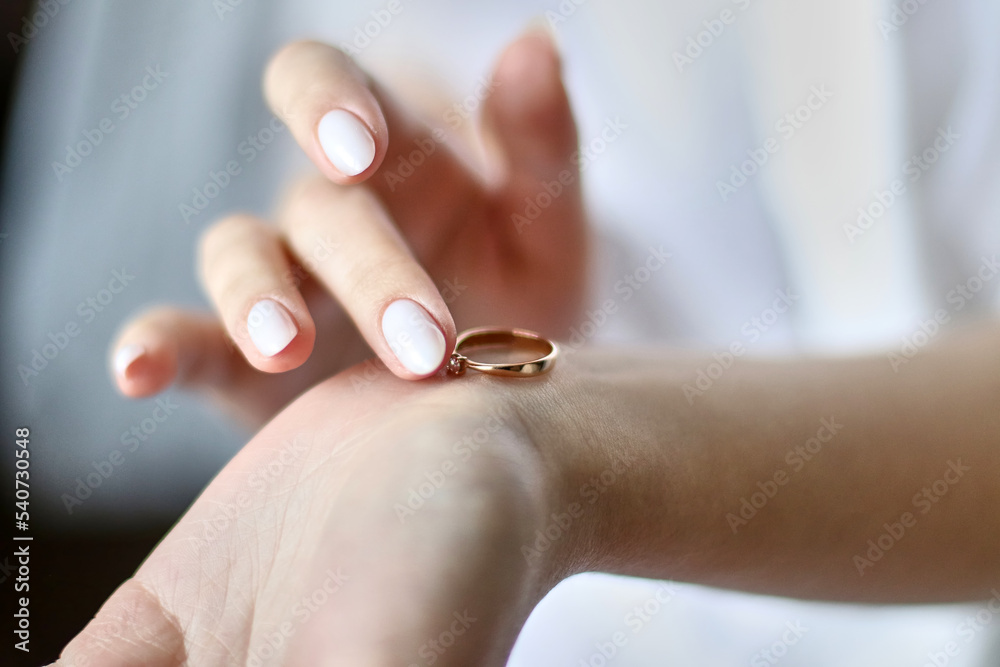 The bride holds a wedding ring in her hands while preparing for the wedding. Preparation and holding of the holiday. The bride holds a wedding ring in her hands while preparing for the wedding. Preparation and holding of the holiday.