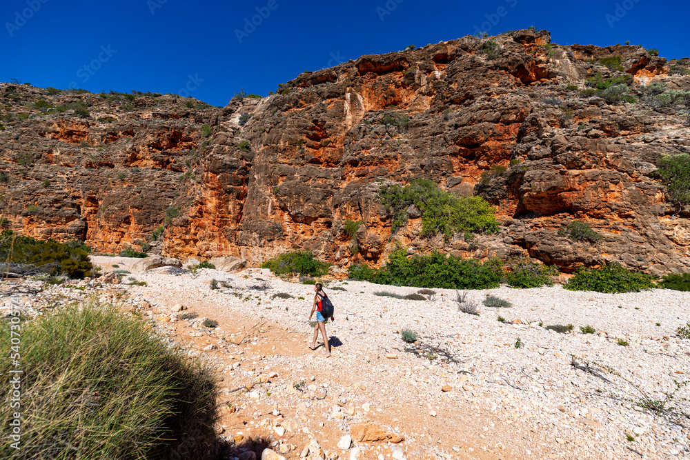 cute tanned girl in short shorts hiking through a gorge in cape range national park in western australia; hiking in the australian outback near exmouth