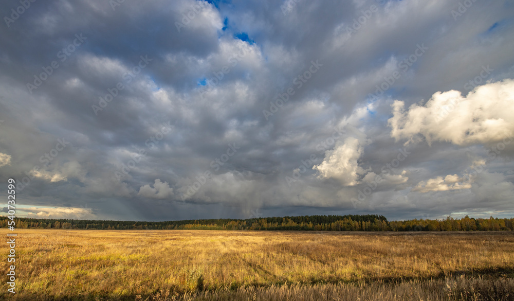 Dramatic sky over the horizon. Autumn landscape, the sun's rays illuminate the field and forest. Bright autumn evening. Dramatic sky over the horizon. Autumn landscape, the sun's rays illuminate the field and forest. Bright autumn evening.
