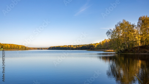 Autumn landscape near the water. The sky is reflected in the pond.