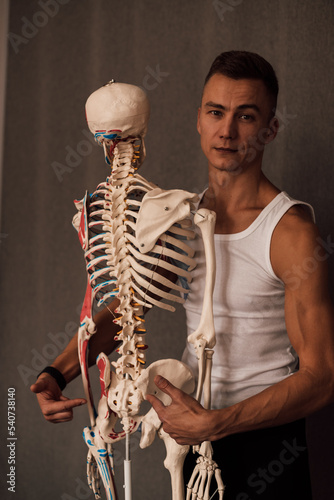 A man in a white T-shirt studies the structure of the human skeleton photo