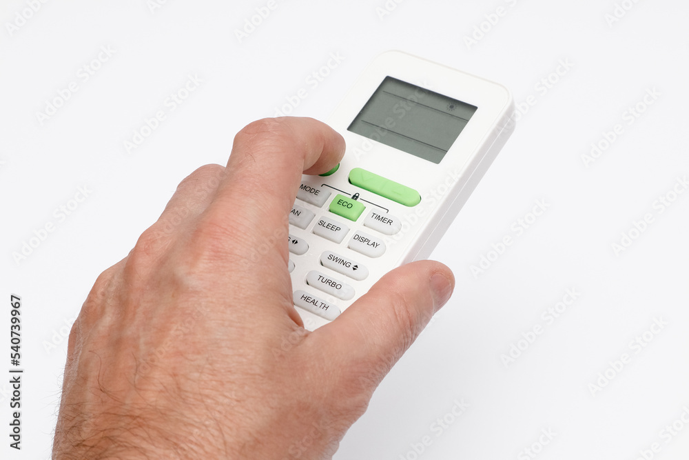 Man's hand using remote controler. Hand holding remote and adjusting temperature of air conditioner mounted on a white wall. Man's hand using remote controler. Hand holding remote and adjusting temperature of air conditioner mounted on a white wall.