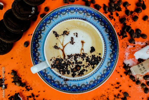 Top view of a Cappuccino with art on an orange table with cookies