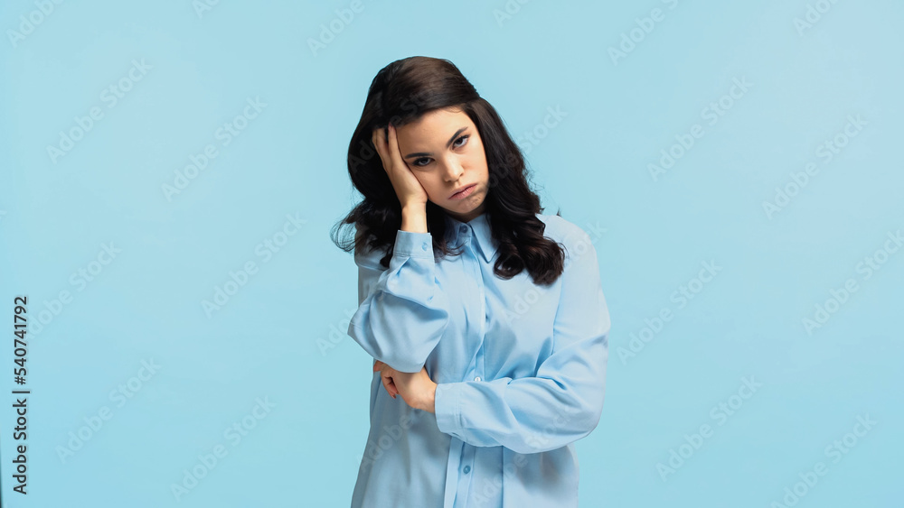 displeased young woman in shirt touching head while puffing cheeks isolated on blue displeased young woman in shirt touching head while puffing cheeks isolated on blue