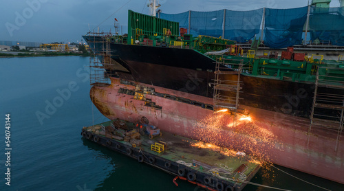 Cargo container ship at dry dock concept maintenance service working in the sea. Insurance and Maintenance Cargo Ship concept. cutting metal of Ship with gas photo