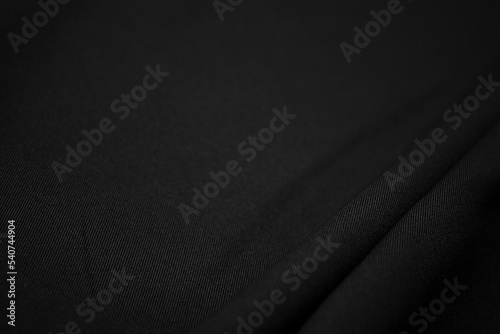 Texture of dark black fabric closeup. Low key photo. Plexus threads. Clothing industry. Abstract background. Black textile waves. Black cloth background