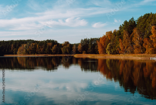 Autumn multi-colored mixed forest and sky with clouds is reflected in the surface of the water of Lake Baltieji Lakajai in Labanoras Regional Park, Lithuania