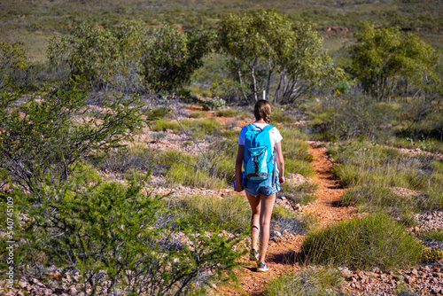 fit girl with backpack hiking uphill on red rocks in cape range national park in western australia, hiking in australian outback, australian desert