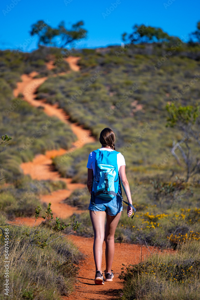 Naklejka premium fit girl with backpack hiking uphill on red rocks in cape range national park in western australia, hiking in australian outback, australian desert