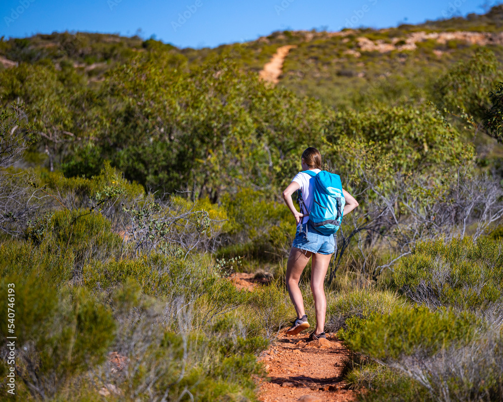 Naklejka premium fit girl with backpack hiking uphill on red rocks in cape range national park in western australia, hiking in australian outback, australian desert
