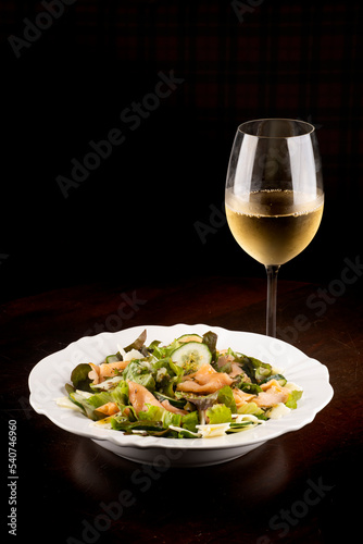 Salad plates with cucumber and salmon on wooden table healthy eating with glass of white green wine