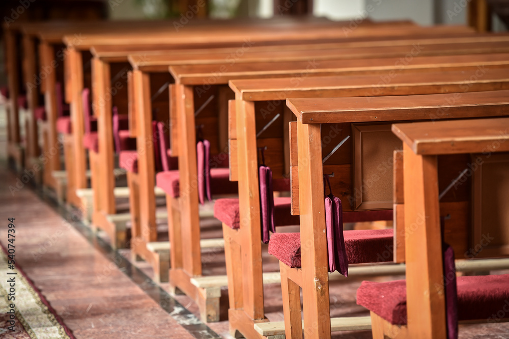 Detail with wooden prayer benches in a row inside a catholic church