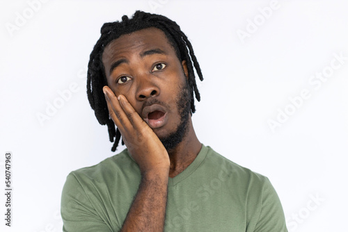 Portrait of surprised African American man leaning on hand. Shocked young male model with braided dark hair in green T-shirt looking at camera, reacting to news or ads. Shock, advertisement concept.