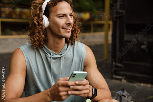 Cropped portrait of young handsome smiling sporty man in headphones