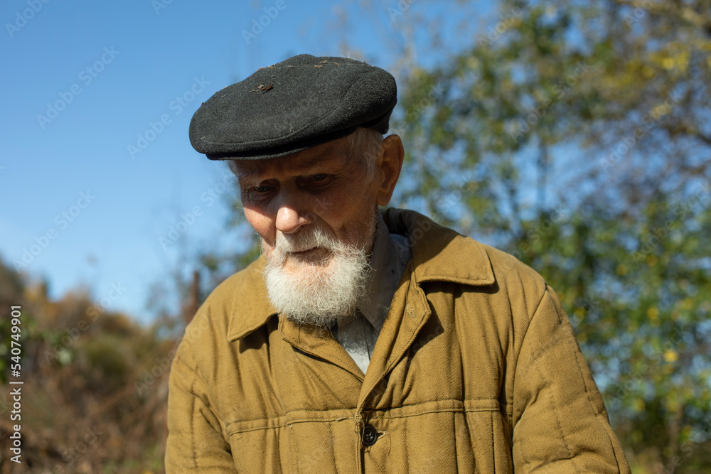 Old man with gray beard and cap. Man of 92 years. Old man in garden. Old man with gray beard and cap. Man of 92 years. Old man in garden.
