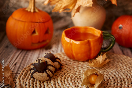 Aesthetics Halloween spider cookies and cup of tea among pumpkins and fragrant leaves