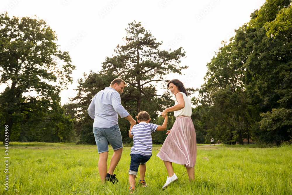 Happy family parents and son spending time in park at summer Happy family parents and son spending time in park at summer