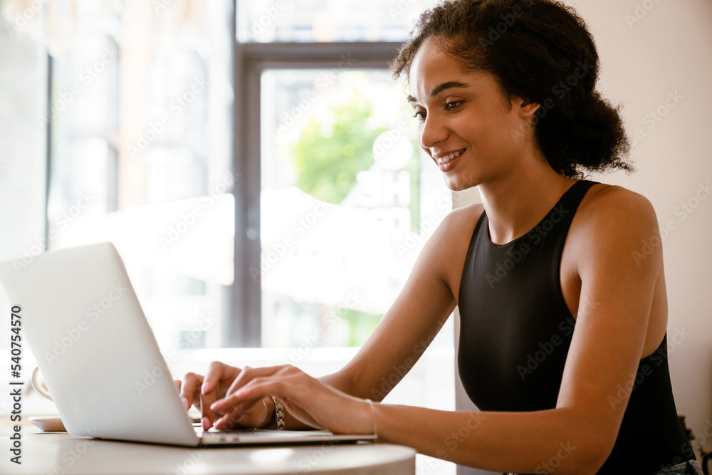 Brunette young woman working with laptop while sitting in cafe Brunette young woman working with laptop while sitting in cafe