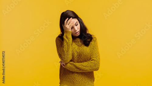upset and brunette woman in sweater touching forehead isolated on yellow © LIGHTFIELD STUDIOS