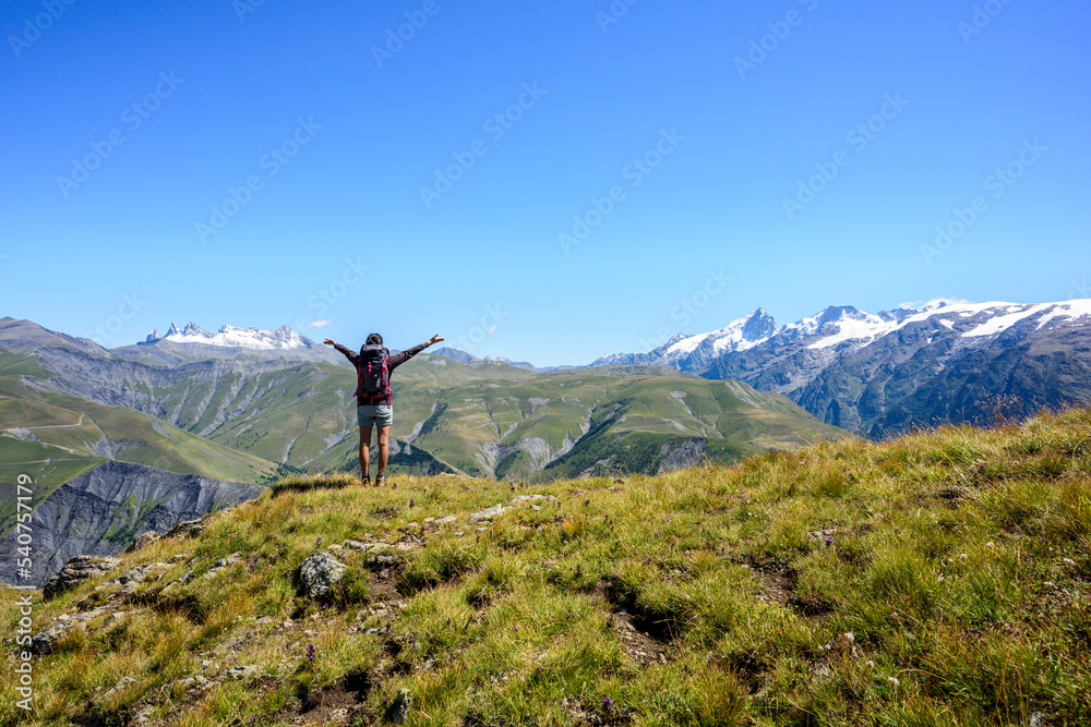 Happy woman hiker enjoying the scenic view at the top of a mountain during summer, French Alps