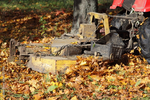 Lawn mover machine tractor mowing the grass under yellow foliage in autumn Park  photo