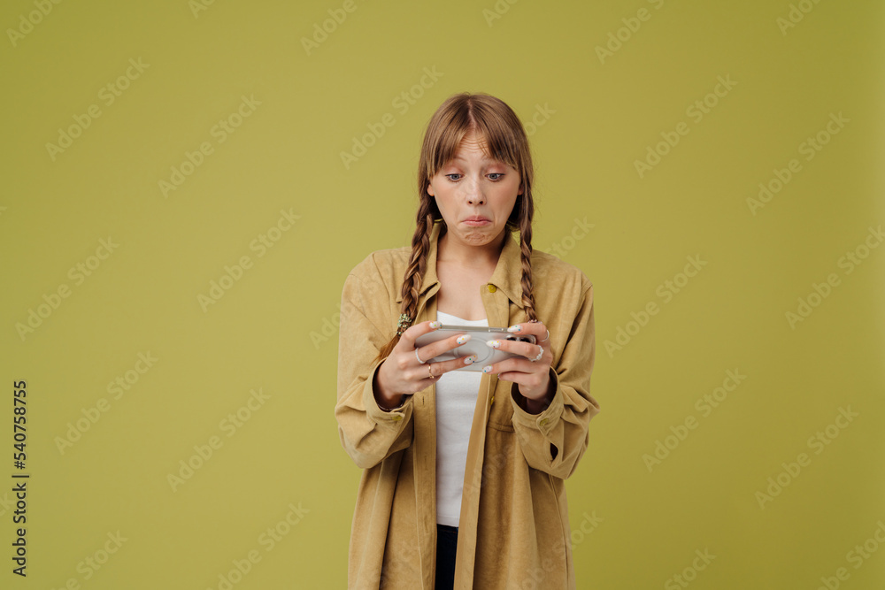 Perplexed blonde woman playing online game on mobile phone Perplexed blonde woman playing online game on mobile phone
