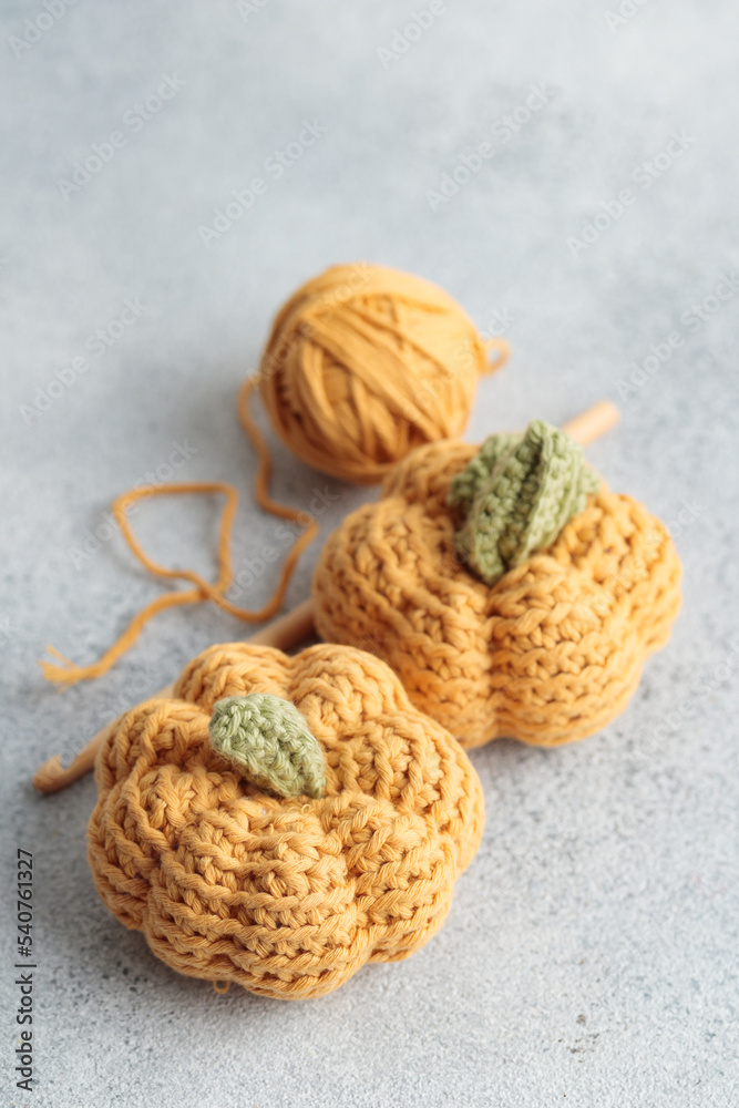 Cute crochet knitted yellow pumpkins on gray background
