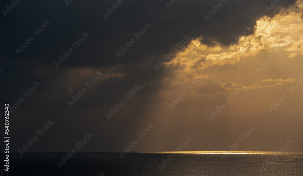 Sunrise in the sea with cloud stormy clouds and orange colour. Seascape in the morning. Sun rays in the ocean