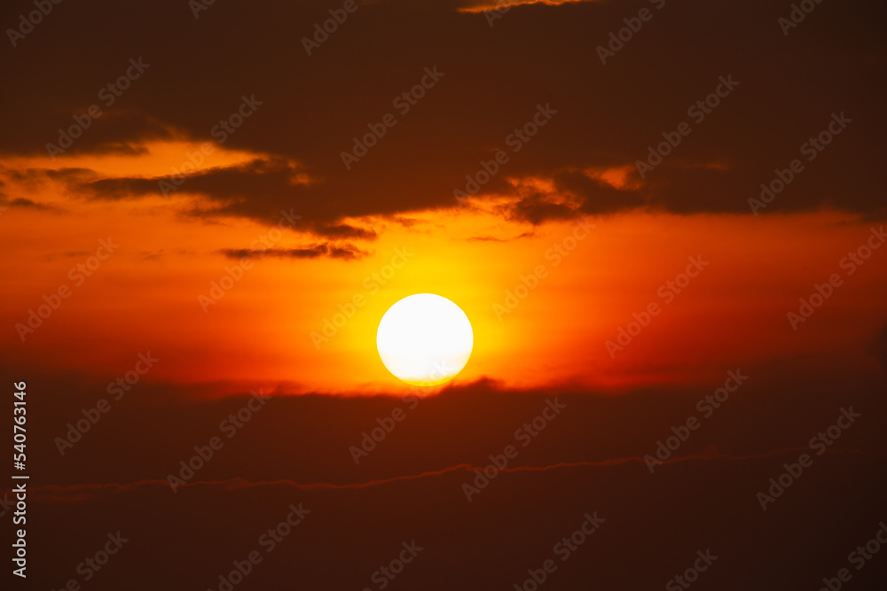 The bright sun shining on the sky and clouds the time in the evening