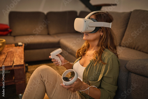Woman playing VR videogame on floor photo