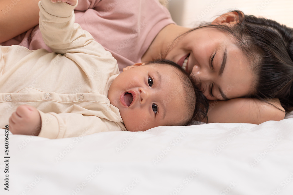 Mom and baby are laying down and cuddling. Mom is kissing her son and both are smiling. Cute baby boy is look so happy and enjoy playing with mom on bed. The baby has chubby and healthy. Good moment Mom and baby are laying down and cuddling. Mom is kissing her son and both are smiling. Cute baby boy is look so happy and enjoy playing with mom on bed. The baby has chubby and healthy. Good moment