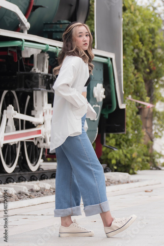 A Thai woman with a casual suit pose over Thai streaming train warming in Bangkok, Thailand.