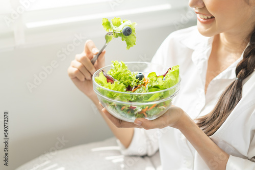 Diet, Dieting asian young woman, girl hand use fork at lettuce on mix vegetables, green salad bowl, eat food low fat to good body sitting on sofa at home. Nutritionist female, Weight loss for healthy.