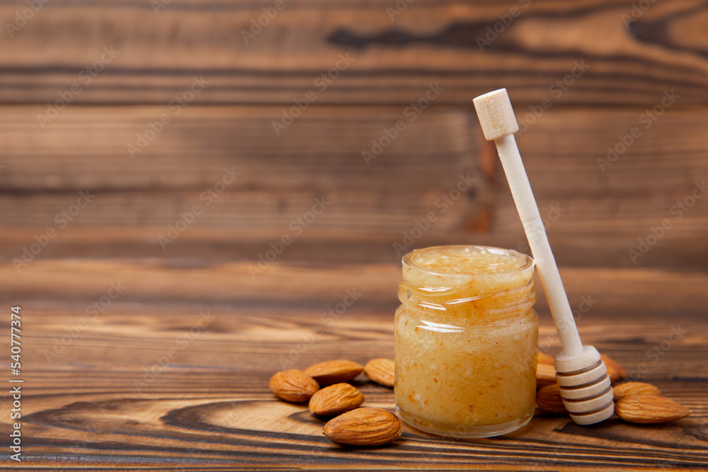Honey in a glass jar. Nutty honey on a brown texture table. Remedy for colds and respiratory diseases. Organic product of a vegetarian diet. copy space. Honey in a glass jar. Nutty honey on a brown texture table. Remedy for colds and respiratory diseases. Organic product of a vegetarian diet. copy space.
