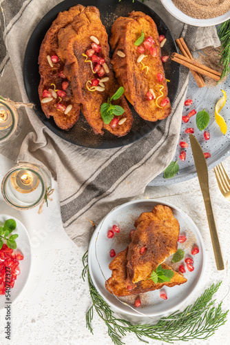 Fototapeta Naklejka Na Ścianę i Meble -  Traditional Christmas Rabanadas with lemon zest, pomegranate, pine nuts and cinnamon. Spanish Torrijas or french toasts close up on the countertop