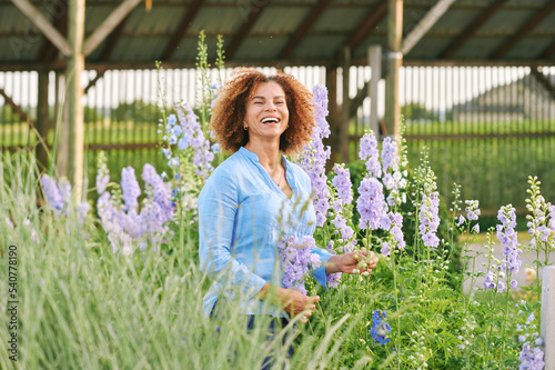 Outdoor portrait of beautiful 50 year old woman enjoying nice day in flower park or garden, happy and healthy lifestyle